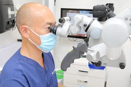マイクロスコープを使用する院長